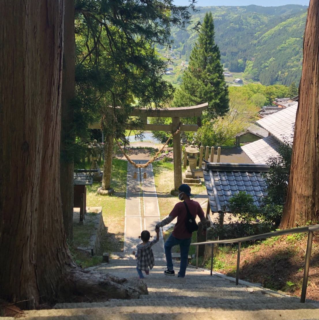 子供と手をつないで神社の階段を降りている所